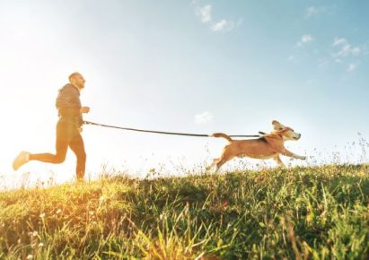 Un homme court avec son chien en laisse